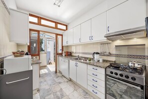 Una cocina moderna con armarios blancos, estufa de acero inoxidable y salpicadero de azulejos.