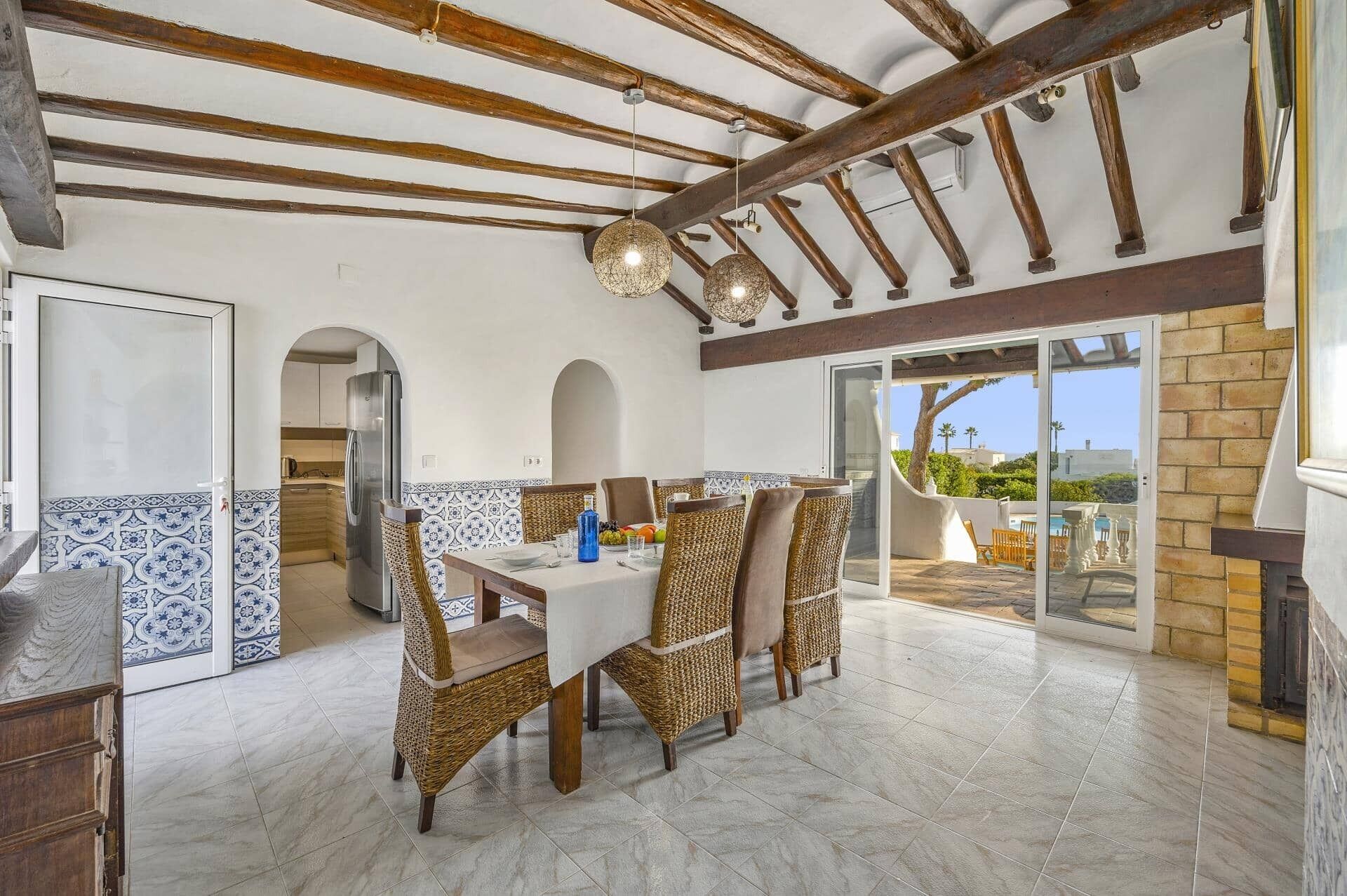 Un comedor amplio con techo alto, vigas de madera a la vista y vistas al exterior.