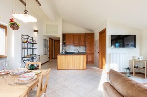 Una cucina moderna con mobili in legno, un'isola centrale e un'area pranzo con tavolo apparecchiato per quattro.