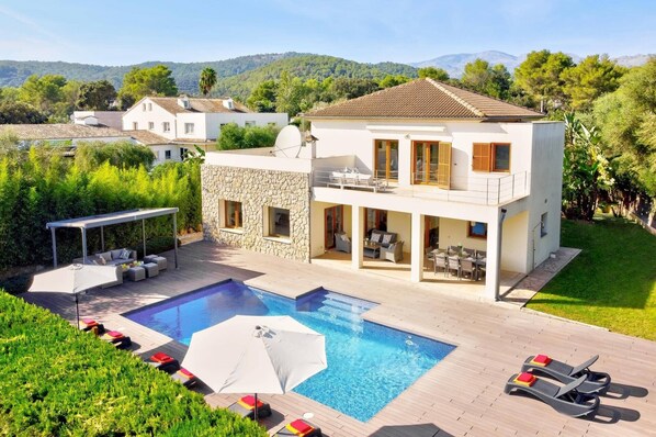 Una casa de dos pisos con piscina, mobiliario exterior y vistas del paisaje circundante.