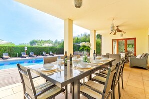 An outdoor dining area with a pool, chairs, and a table set for a meal. - Villa Casa de Pedra by Villa Plus (Crestatx)