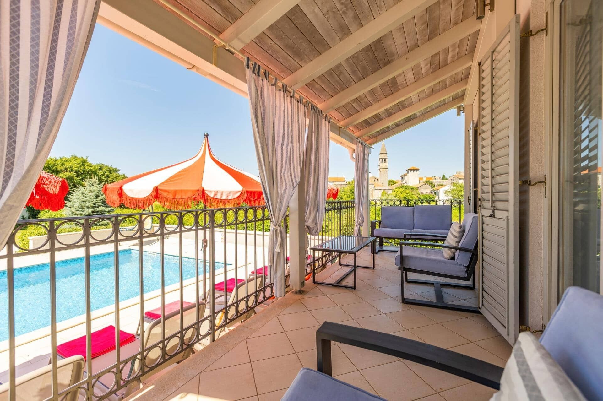 A balcony with a pool, outdoor seating, and a view of a tower.