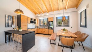Una cocina moderna con armarios de madera, una isla central y una zona de comedor con banco y sillas.