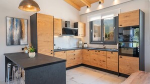 Una cocina moderna con armarios de madera, encimera negra y electrodomésticos de acero inoxidable.