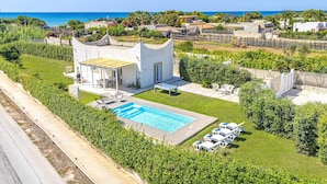 En villa med pool, utomhusmöbler och utsikt över havet.