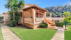 Une maison à deux étages avec une façade en pierre, un balcon doté de volets en bois et un escalier menant à l’étage supérieur.