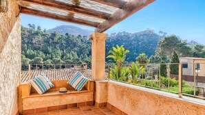 Un balcon doté d’un espace salon avec des coussins, offrant une vue sur un paysage montagneux et doté d’un sol carrelé.