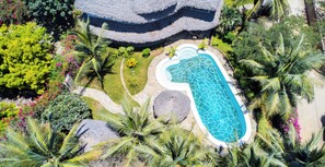 An aerial view of a resort with a swimming pool, lush greenery, and a thatched-roof building. - Villa Jua Suite (Watamu)
