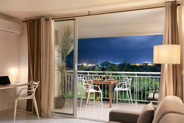 A balcony with a dining table, chairs, a potted plant, and a sofa.