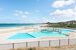 A resort with multiple swimming pools, a beach, and a view of the ocean.