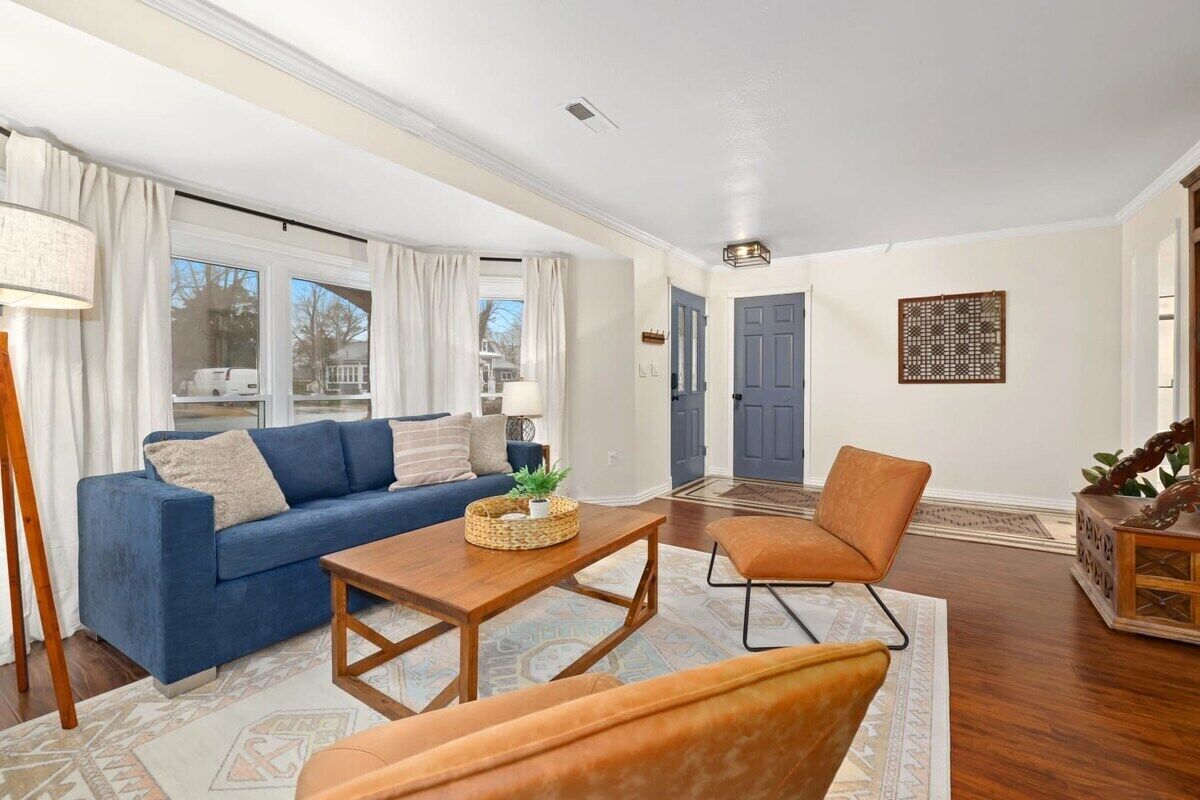 Una sala de estar con un sofá azul, una mesa de centro de madera y un sillón naranja.