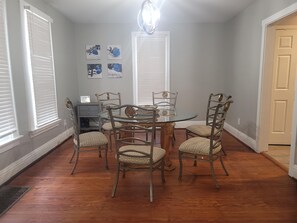 Cozy dining area with a round table and six chairs, featuring framed artwork and a comfortable workspace.