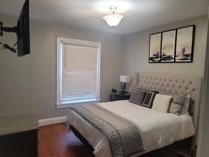Cozy retreat with a large bed, bedside table, and window with blinds.