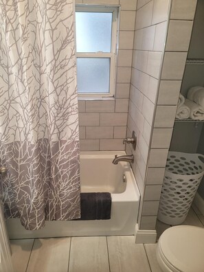 Bathroom features a bathtub, window, and towel rack.