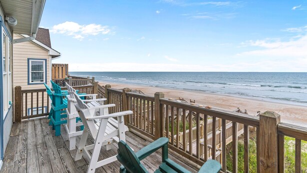 A wooden deck with chairs overlooking a beach.