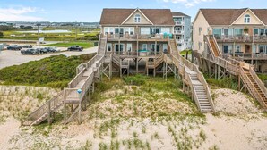 A beachfront hotel with multiple levels, wooden walkways, and a parking area.