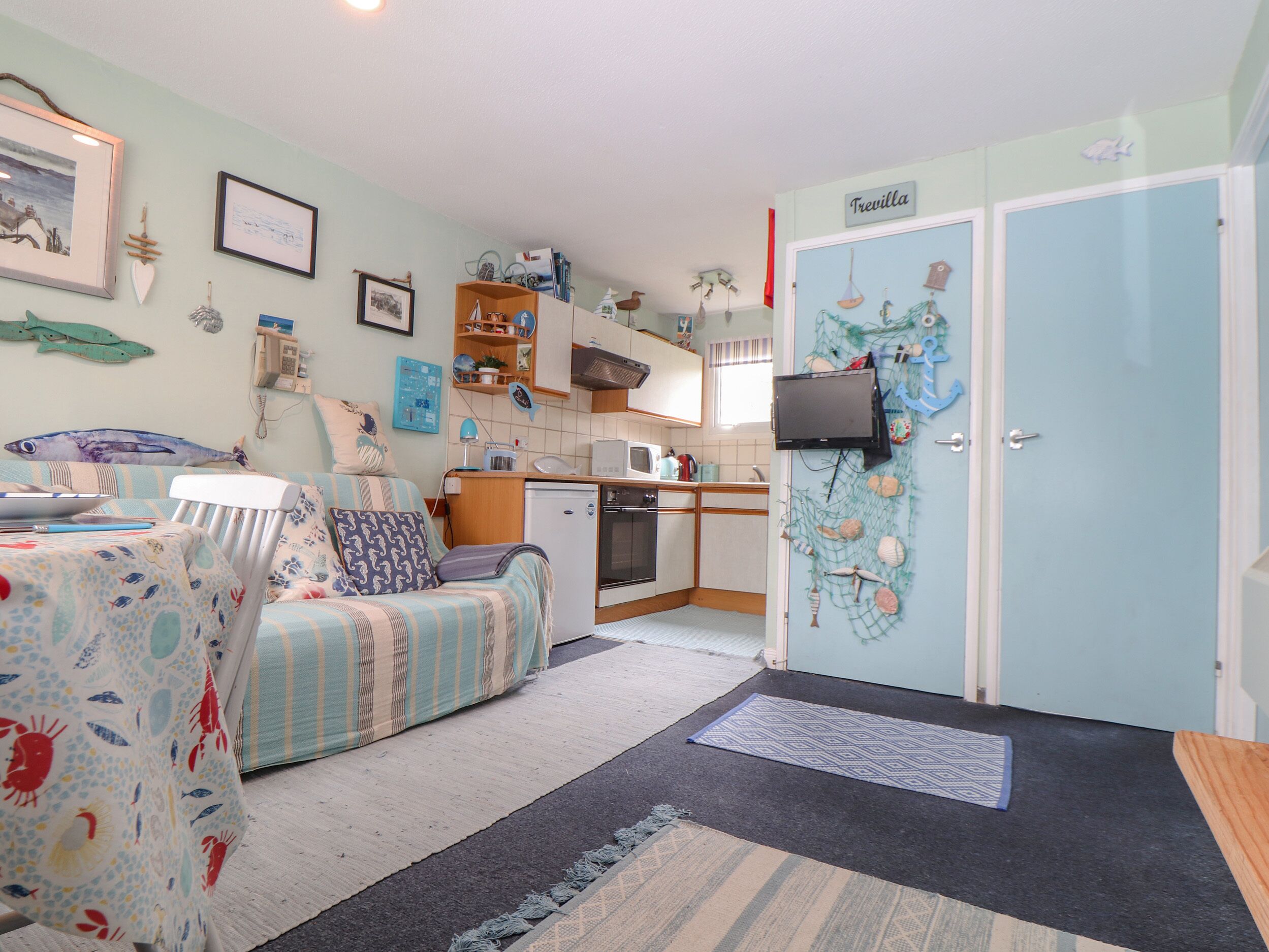 A cozy room with a bed, a small kitchenette, and a door labeled "Trevilla".