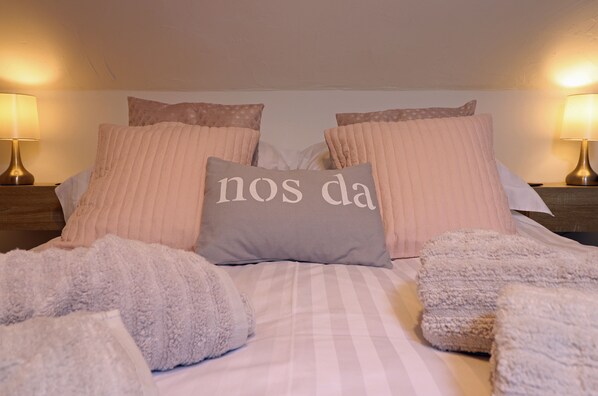 A neatly made bed with striped bedding, multiple pillows, and two bedside lamps. - Bijou House Perfect for 2 people, no pets. (Dolgellau)