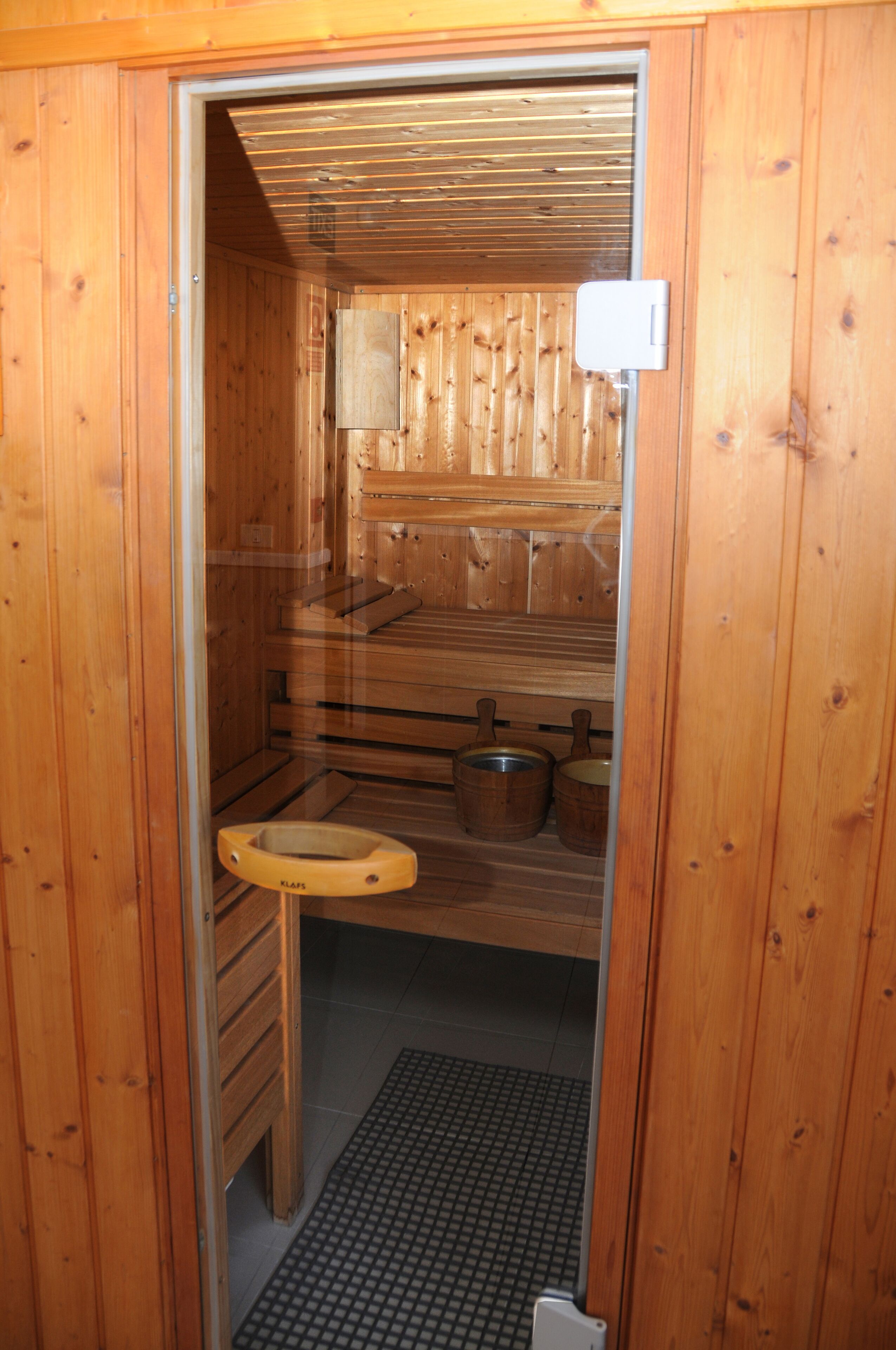 A wooden sauna with a bench, a small table, and a heater.