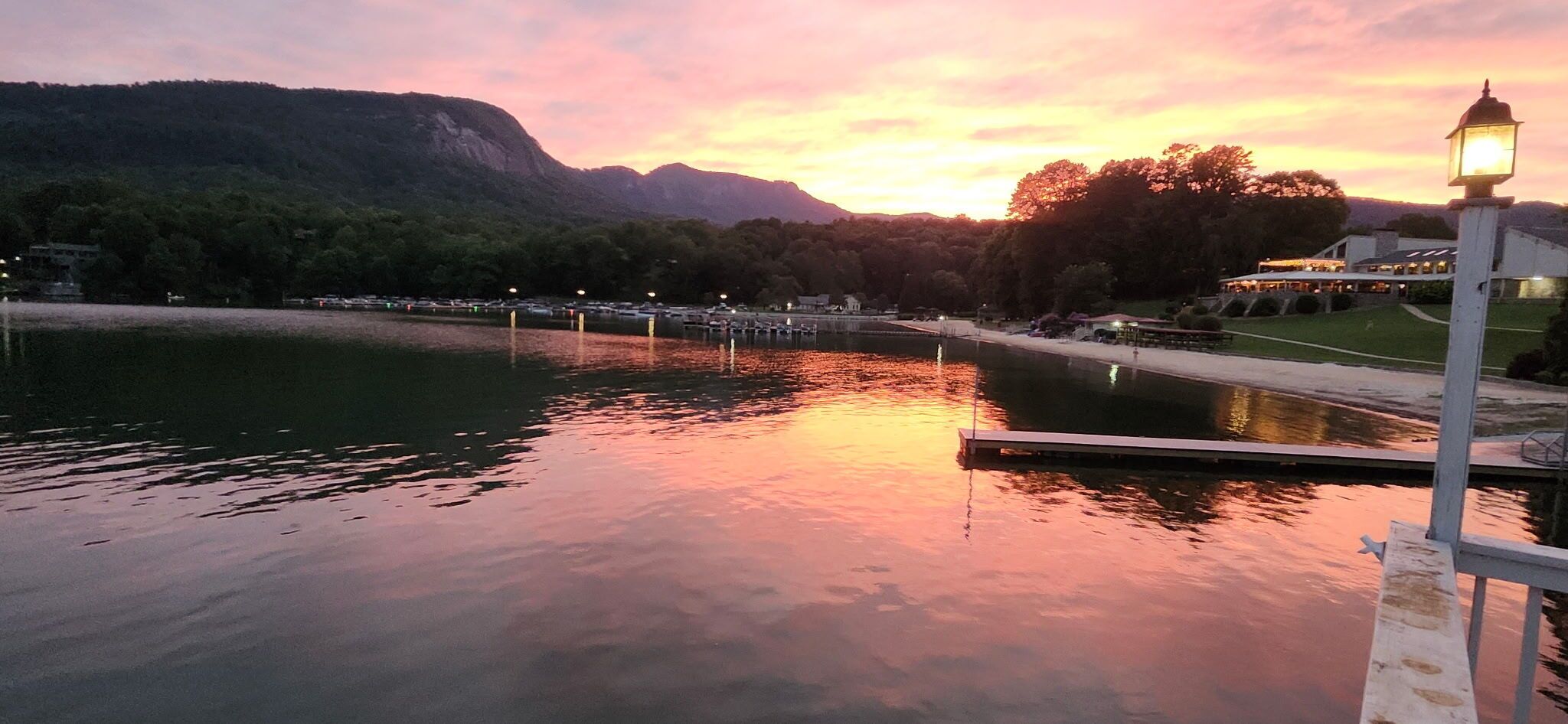 Una vista serena de un lago con un muelle, agua tranquila y un atardecer.