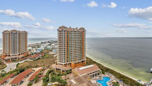 Un hotel costero con dos edificios altos, una piscina y vistas a la playa.