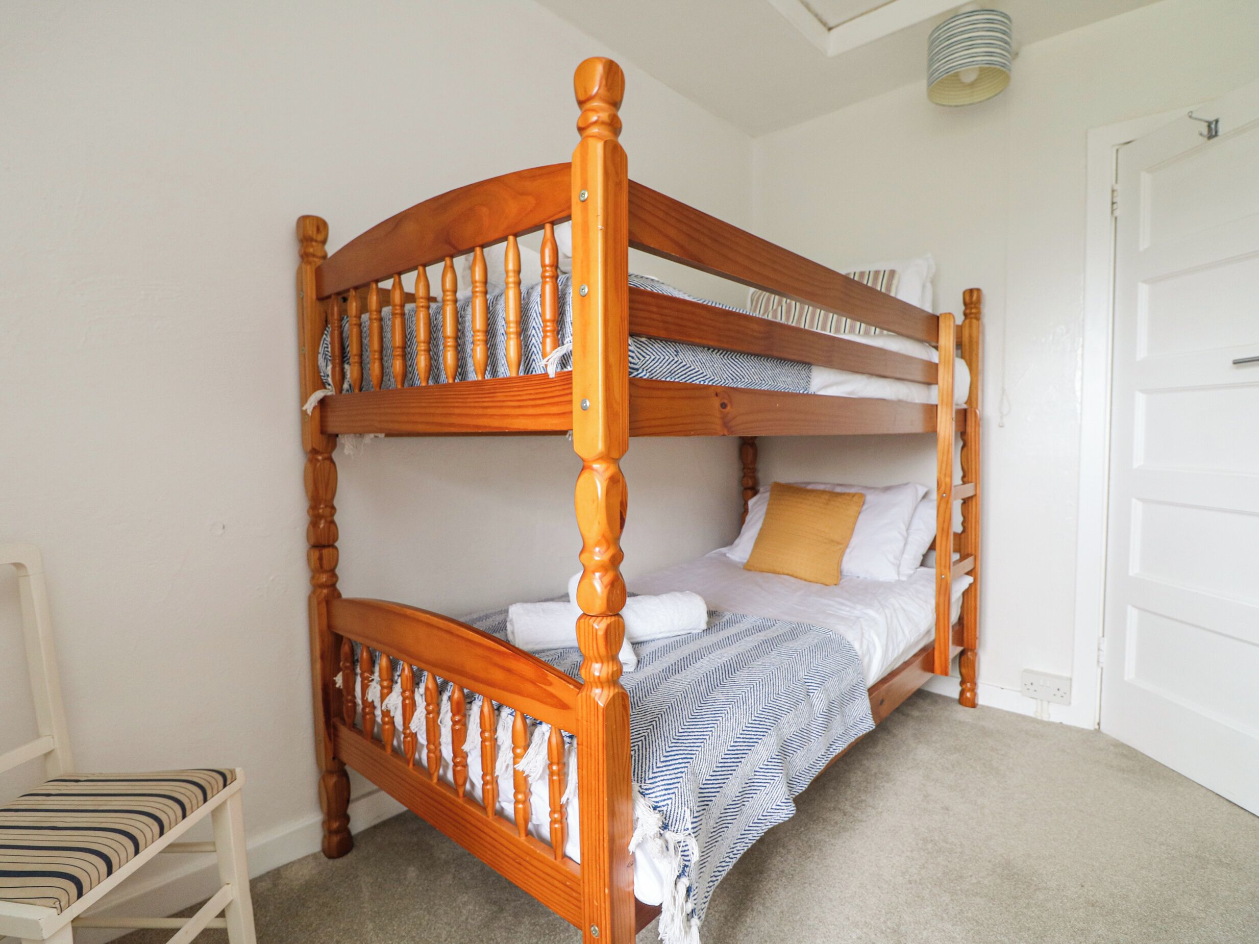 A bunk bed with a wooden frame and a striped cushion.