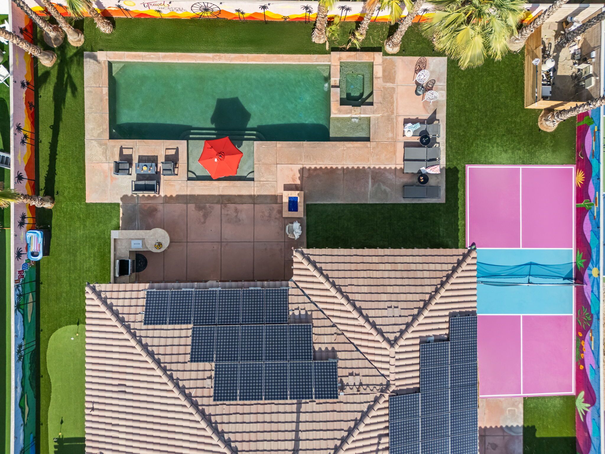 An aerial view of a resort with a swimming pool, outdoor seating, and solar panels.