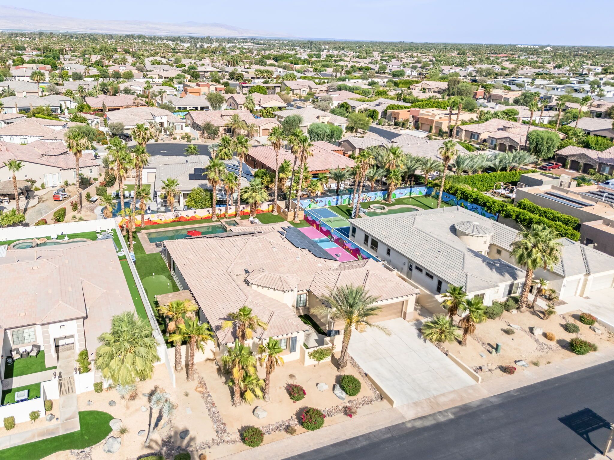 A residential area with houses, palm trees, and a swimming pool.