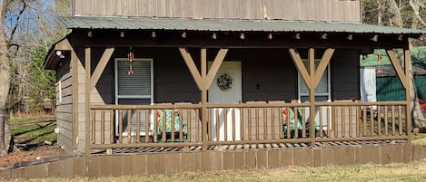 Une cabane en bois rustique, dotée d’un porche, d’une porte et d’une petite fenêtre.
