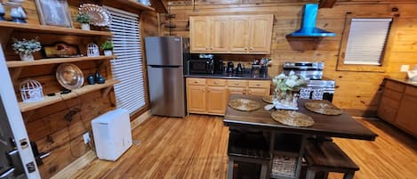 Une cuisine aux murs lambrissés, dotée d’un îlot central, de meubles de rangement en bois et d’un réfrigérateur en acier inoxydable.