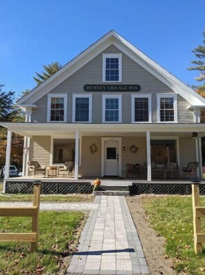 Welcome to Rumney Village Inn, where guests can enjoy a covered porch with seating and a small table.