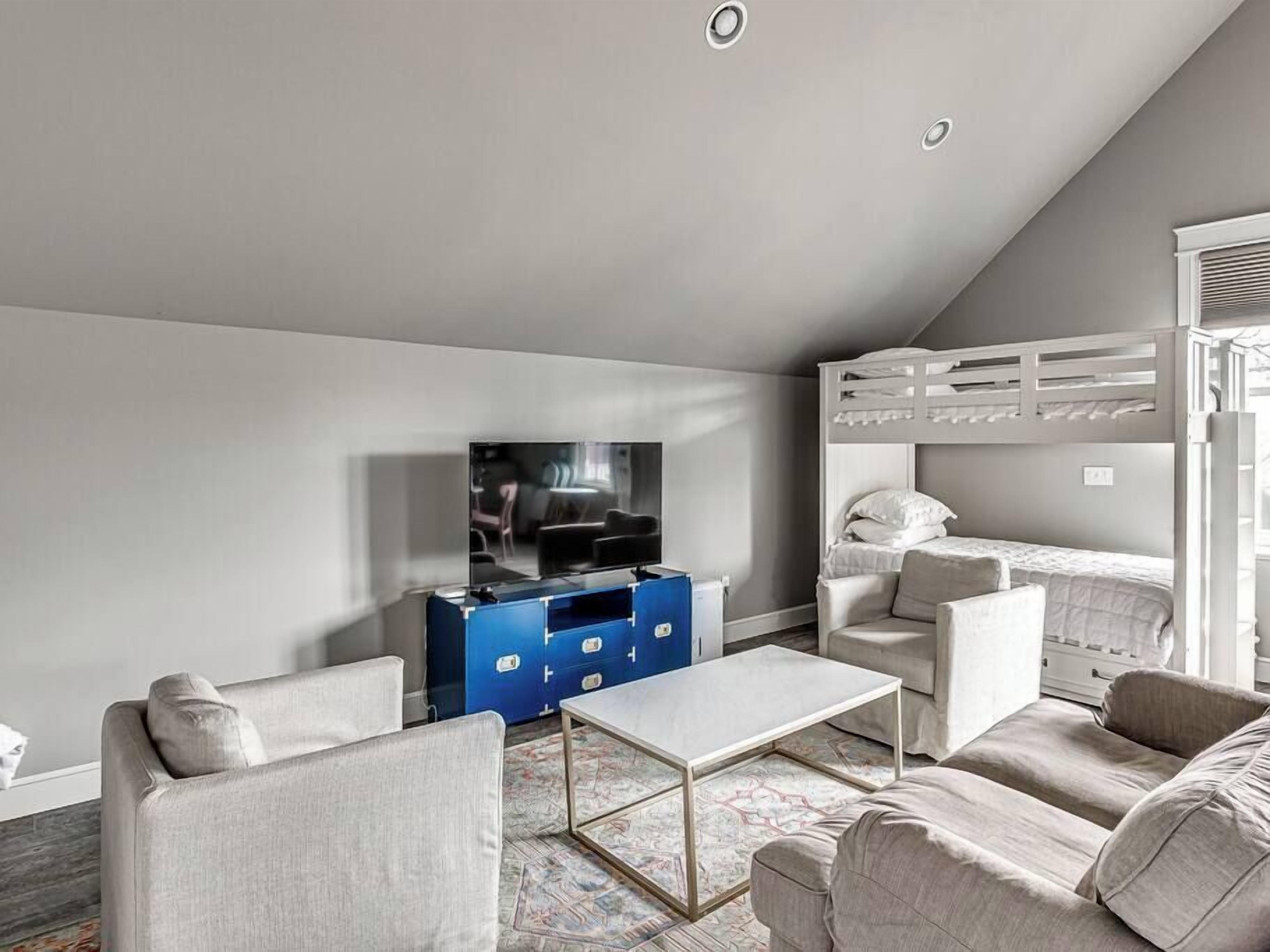 A modern living room with a sofa, a coffee table, a TV, and a bunk bed.