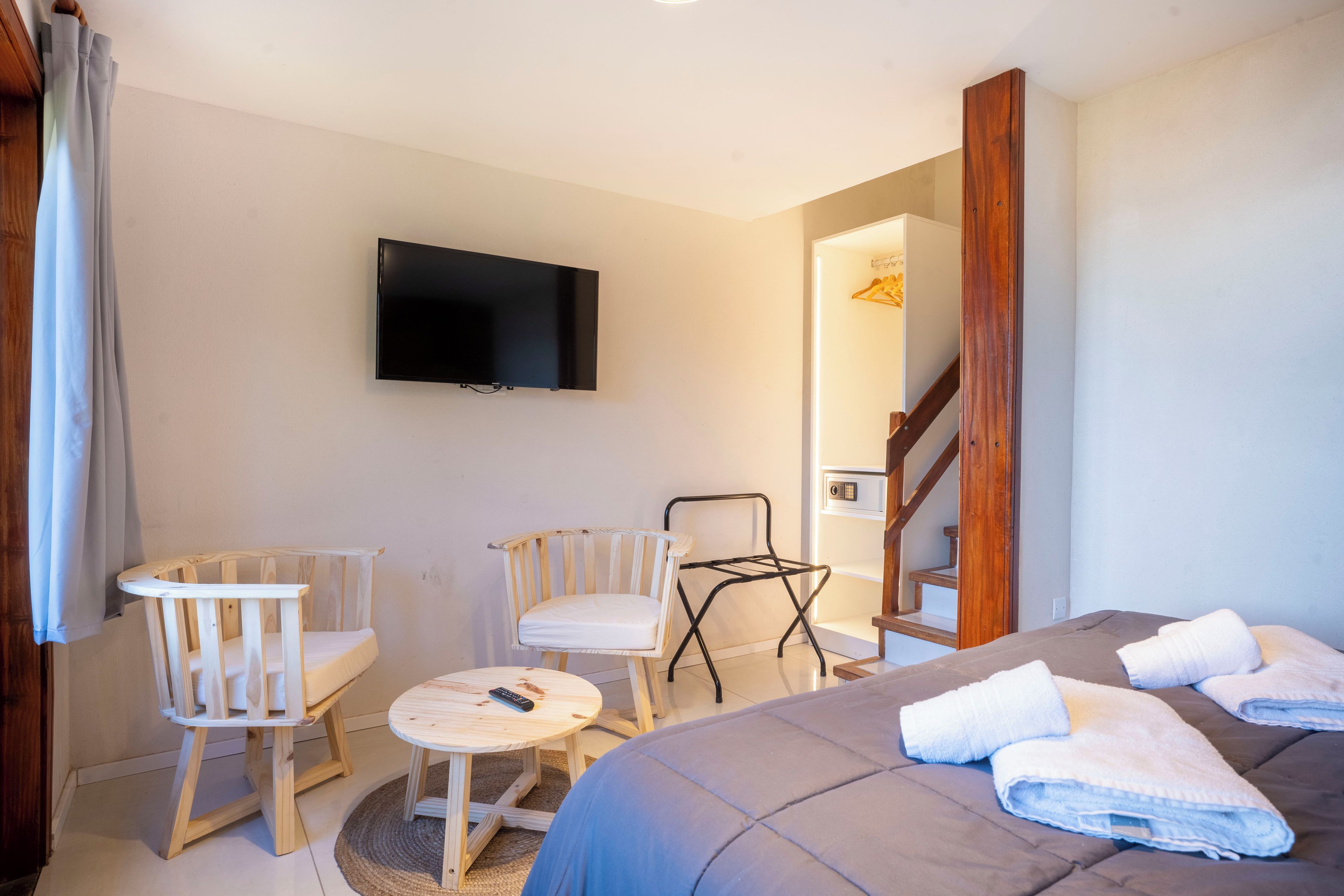 Une chambre d’hôtel avec un lit, deux chaises, une petite table, un téléviseur et un escalier.