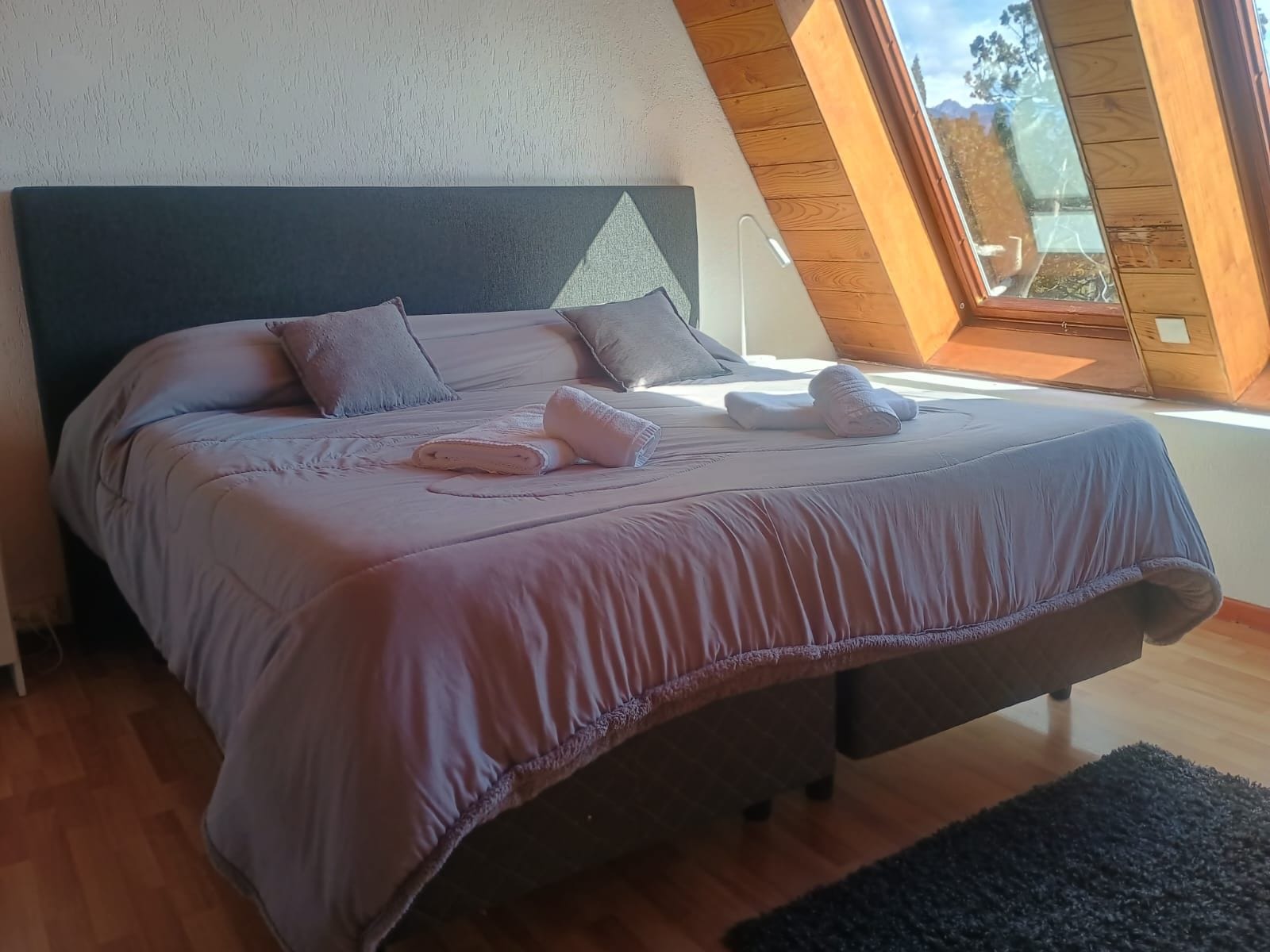 Ein Schlafzimmer mit Bett, Kissen und einem Fenster mit Ausblick.