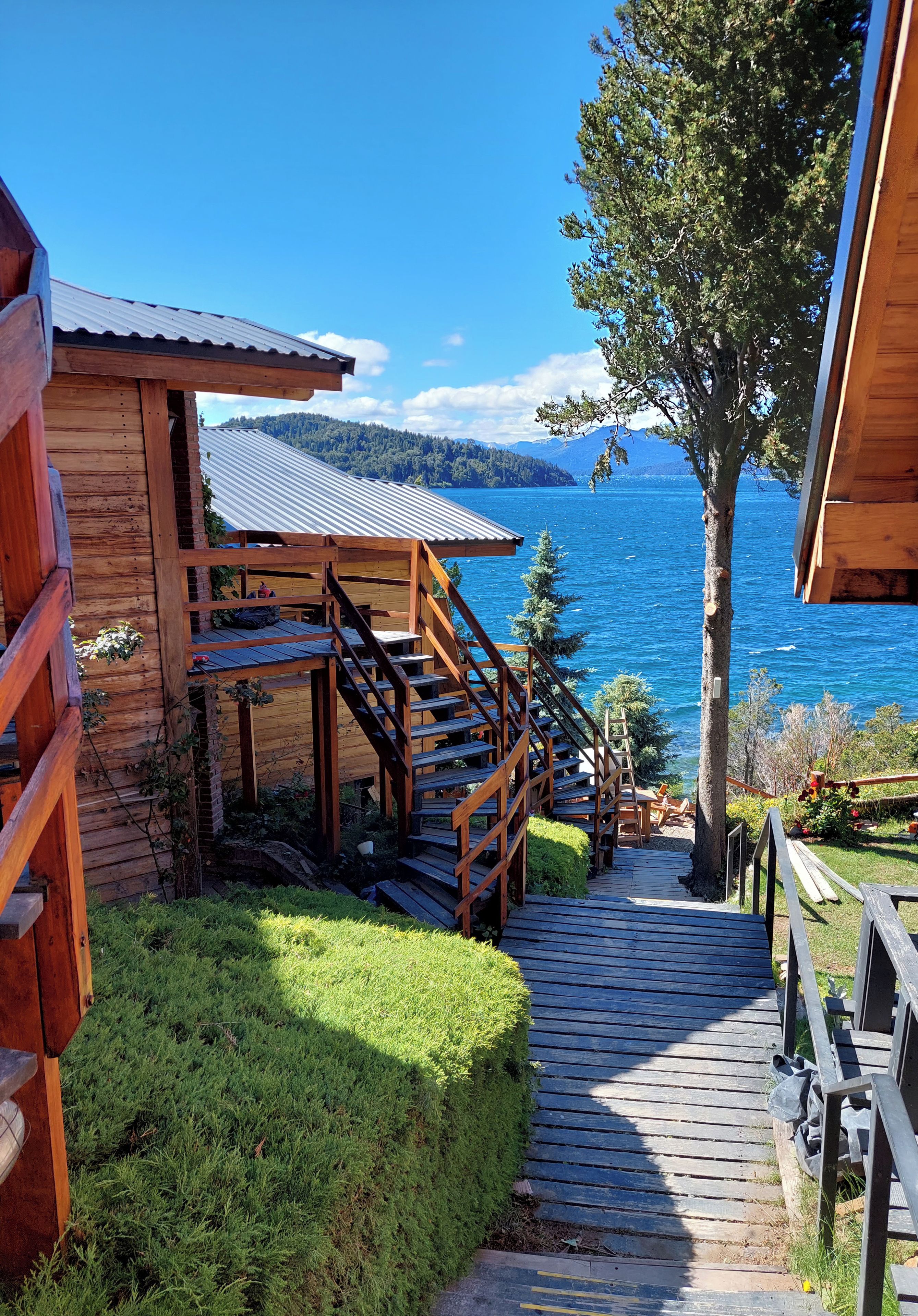A wooden cabin with a staircase leading to a deck overlooking a body of water.