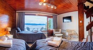 Una cabaña con cama, dos sillas, una mesa, un televisor y vista a un lago.