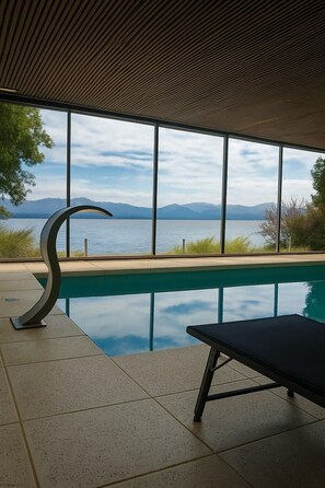Zona de piscina con vistas a montañas y un cuerpo de agua.