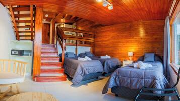 A wooden cabin with two beds, a staircase, and a small seating area.