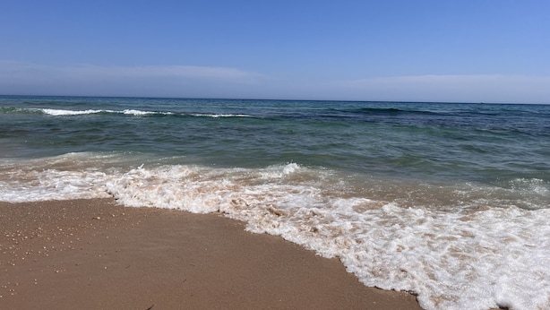 Une plage où les vagues viennent doucement lécher le rivage.