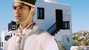 A person in traditional attire standing in front of a modern building with a staircase and a sign that reads "Sle".