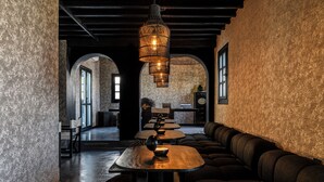 A modern interior with a long communal table, cushioned seating, and a hanging light fixture. - She Mykonos - The Residency (Mykonos)