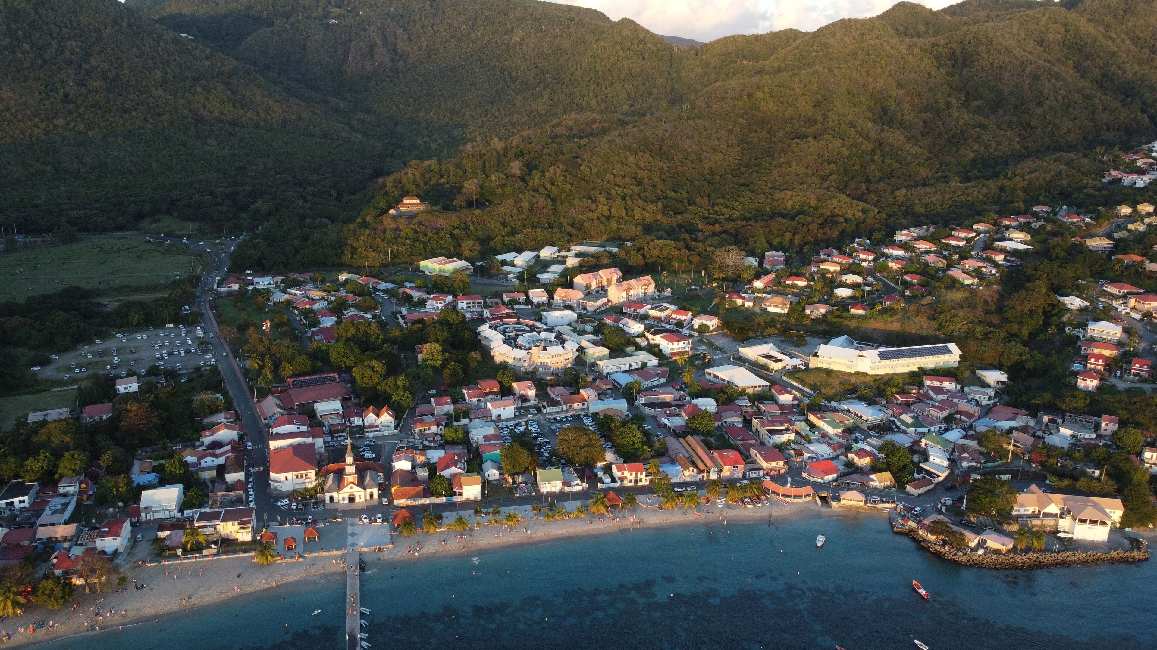An aerial view of a coastal town with a beach, residential buildings, and a prominent church.