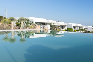 Un hotel moderno con piscina cristalina que refleja el edificio y palmeras.