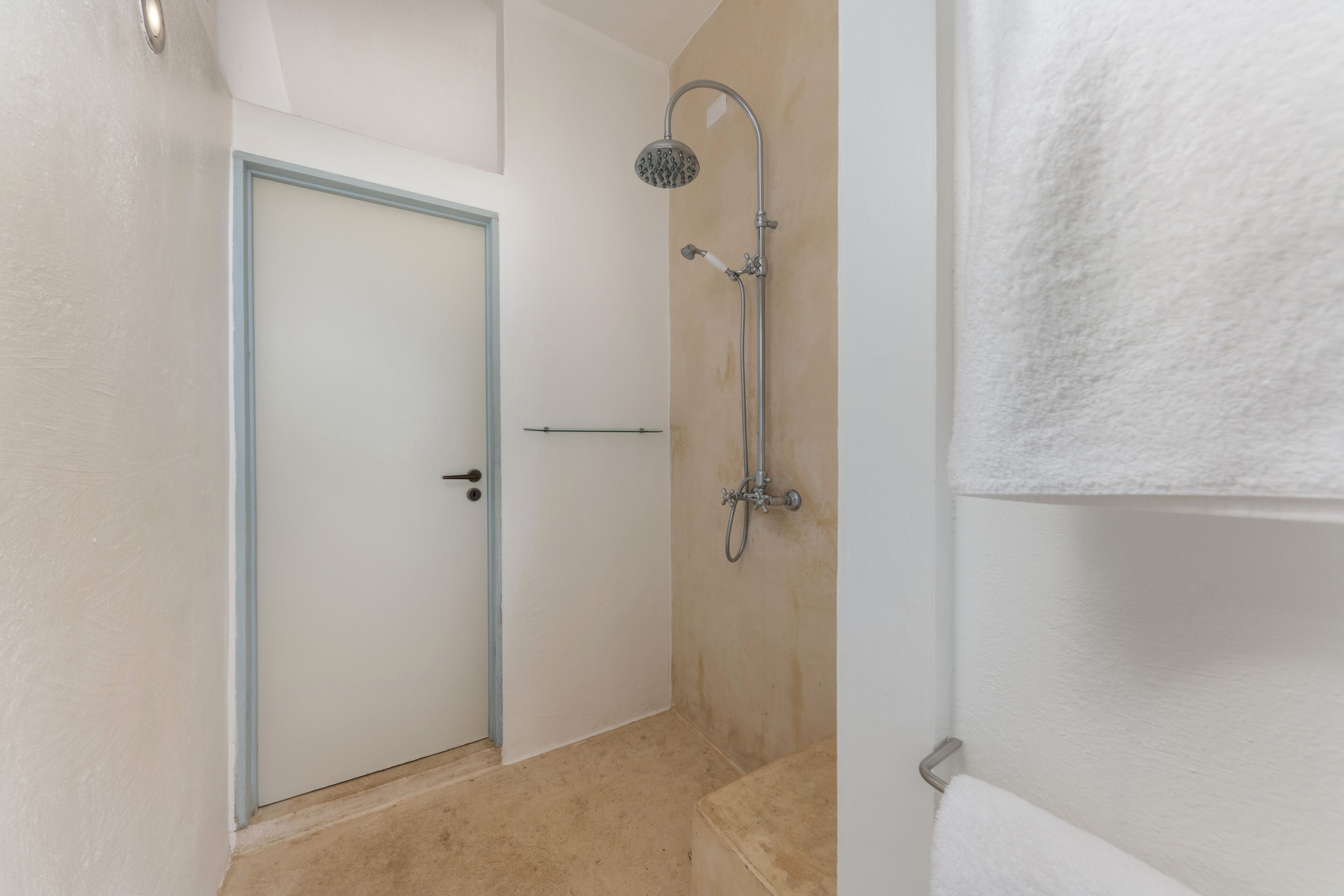 A small, clean bathroom with a shower, a towel rack, and a door.