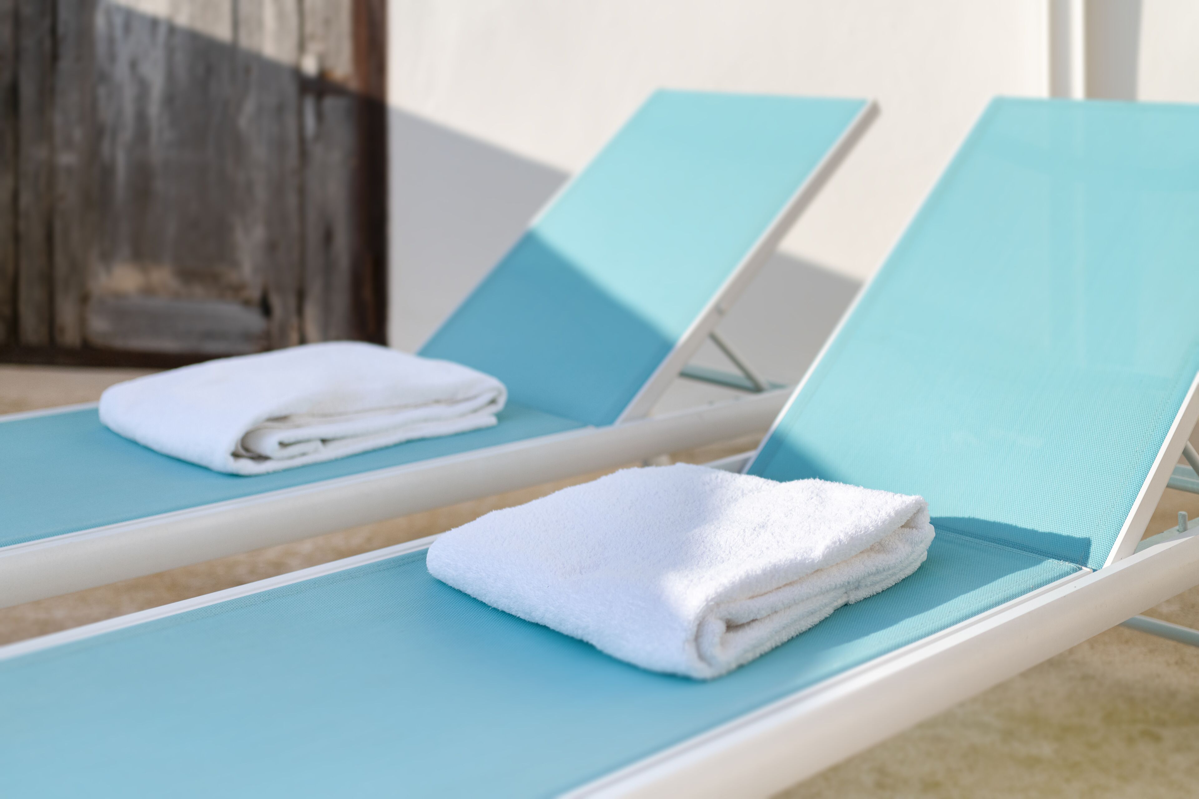 Two blue lounge chairs with white towels folded on them.