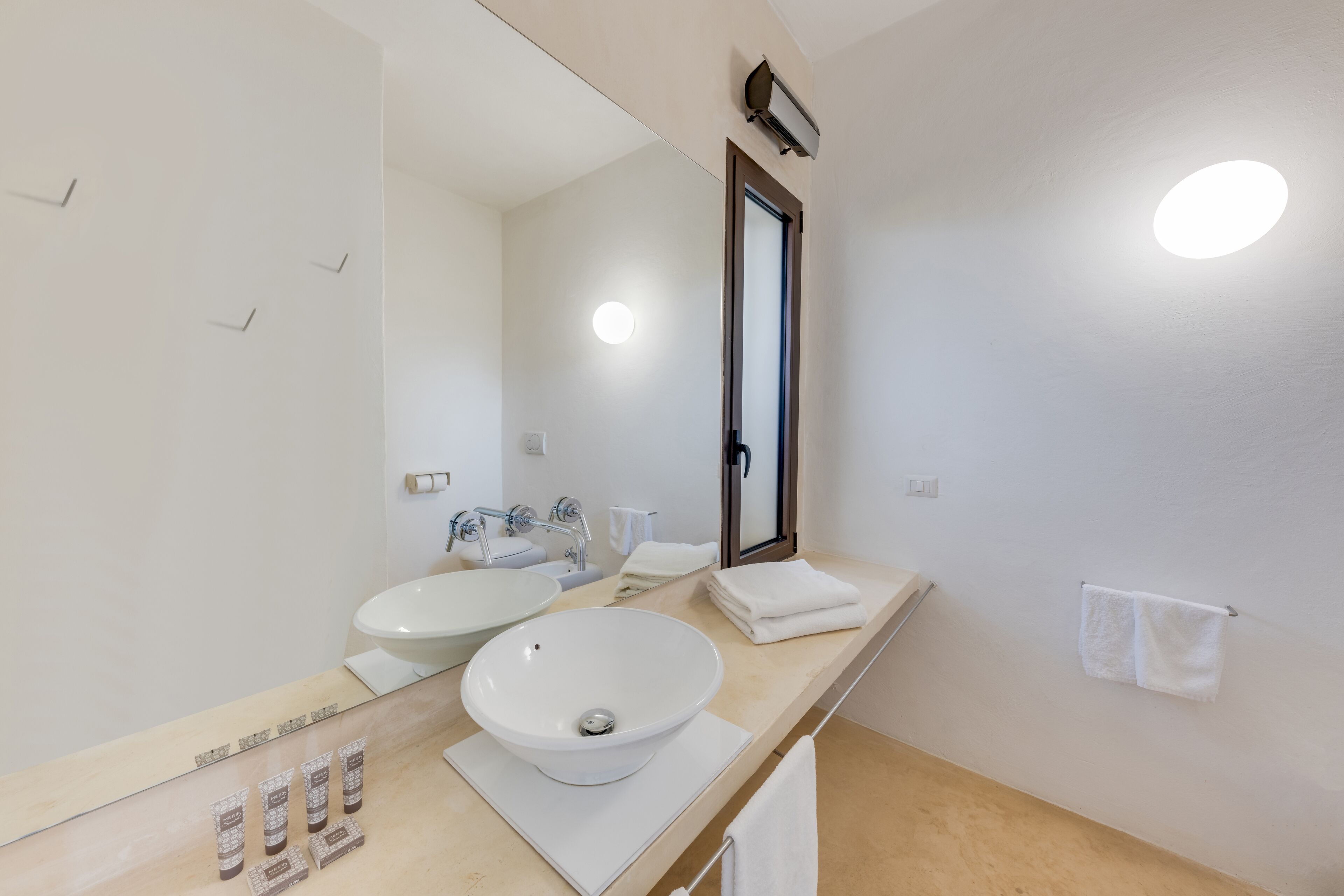 Een moderne badkamer met een grote spiegel, twee wastafels en een handdoekrek.