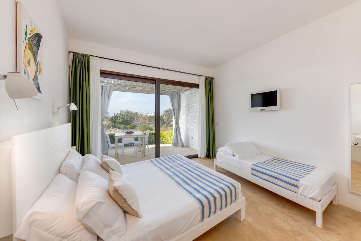 Une chambre d’hôtel avec deux lits, une télévision et un balcon équipé d’une table et de chaises.