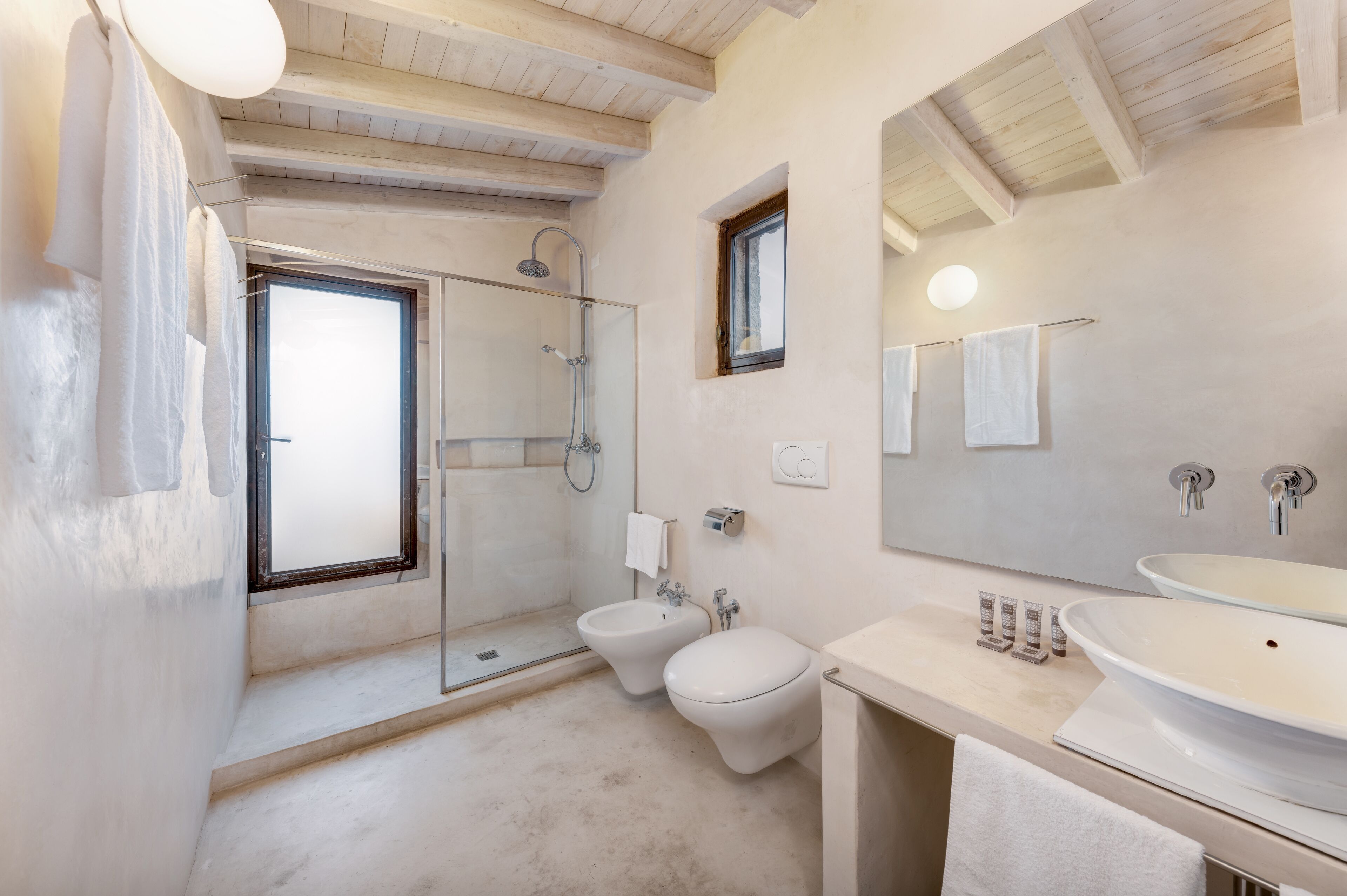 Un bagno moderno con doccia in vetro, un bidet, un water e un ampio lavandino.
