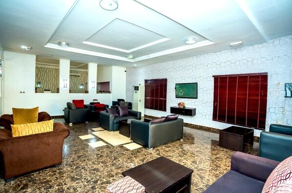 Een ruime lobby met een hoge plafond, modern meubilair en een behang met patroon.