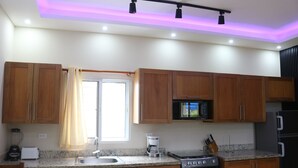 Una cocina moderna con armarios de madera, microondas integrado, estufa y lavamanos.